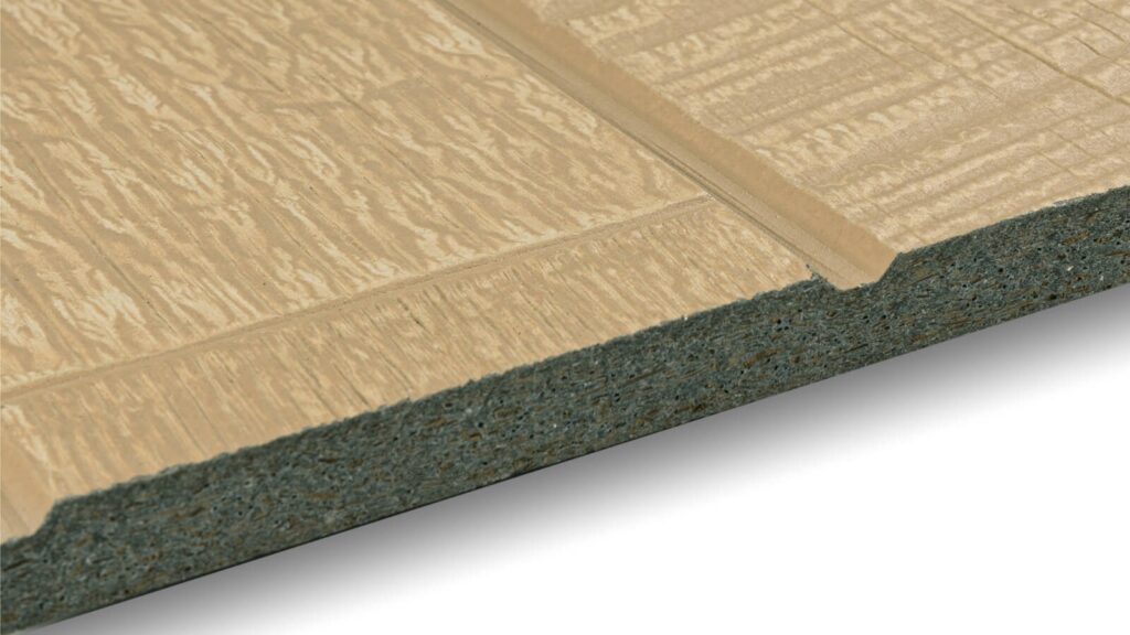 A close-up view of a beige textured fiber cement siding panel with wood grain design and a tapered edge. The panel is shown angled slightly from the side, revealing its layered composition.