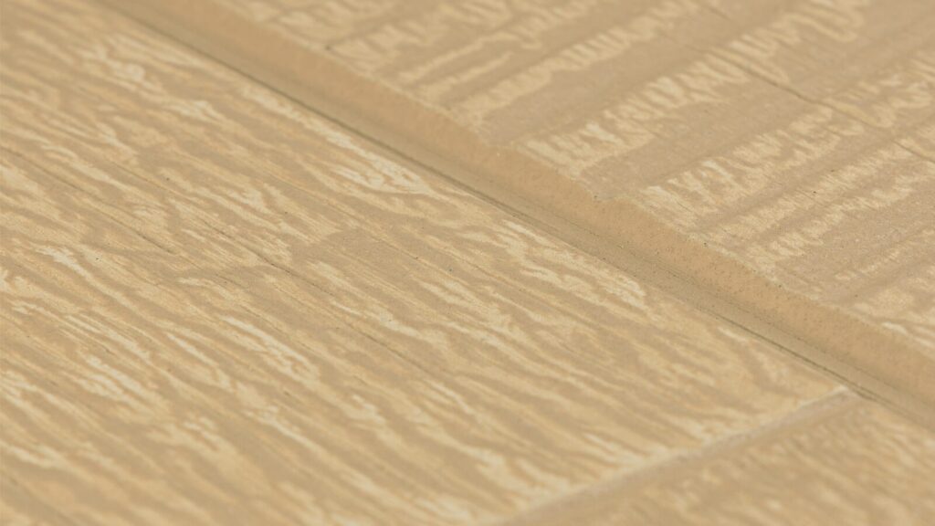 Close-up image of a light brown textured surface resembling wood grain, with visible grooves and patterns running horizontally and vertically, intersecting at regular intervals. The surface has a natural, rustic appearance.