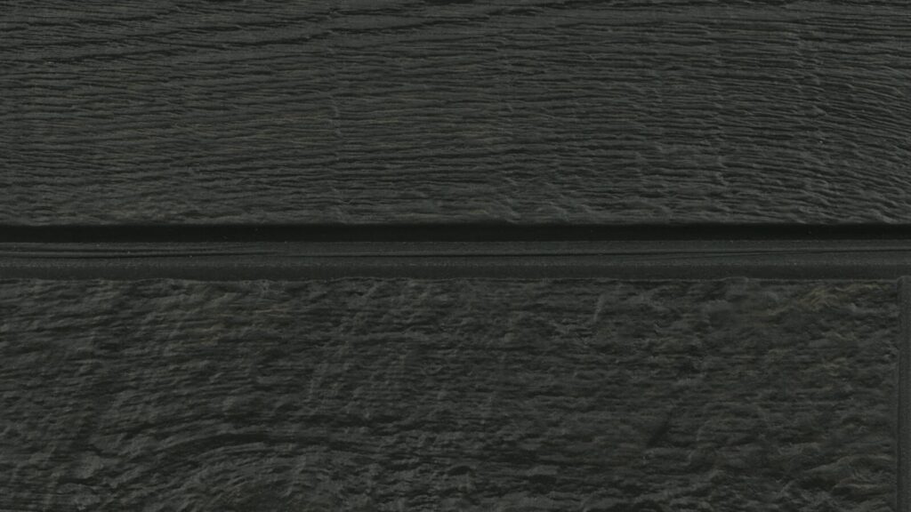 Close-up of a textured black wooden surface with horizontal grooves running across. The wood grain is visible, providing a rugged and natural appearance. The color is consistent and dark throughout the image.
