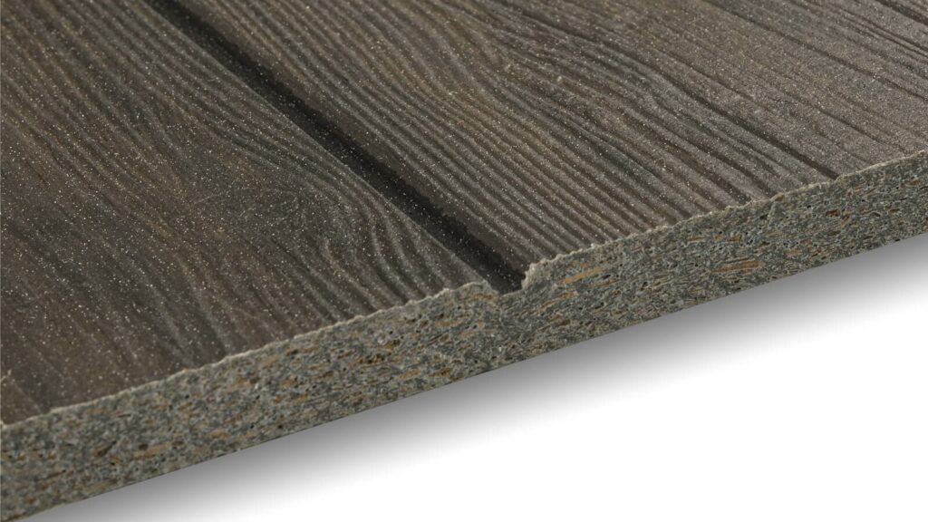 Close-up image of a wood-textured, composite material panel, showcasing detailed grain patterns and a precise edge cut. The panel has a dark, weathered finish with visible grooves that add depth and a tactile quality to the surface.