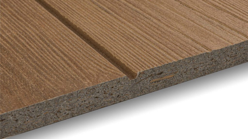 Close-up view of a piece of composite decking material with a wood-like texture and parallel grooves running along its surface. The edges reveal a layered structure, showcasing the engineered composition of the decking board.