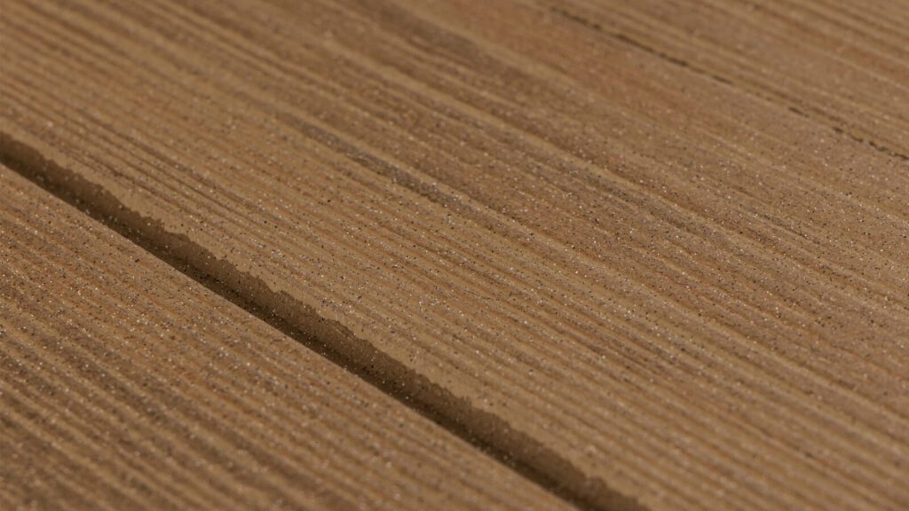 Close-up image of a wood surface showcasing its textured grain. The wood features subtle lines and natural color variations, highlighting its organic pattern and fine details.